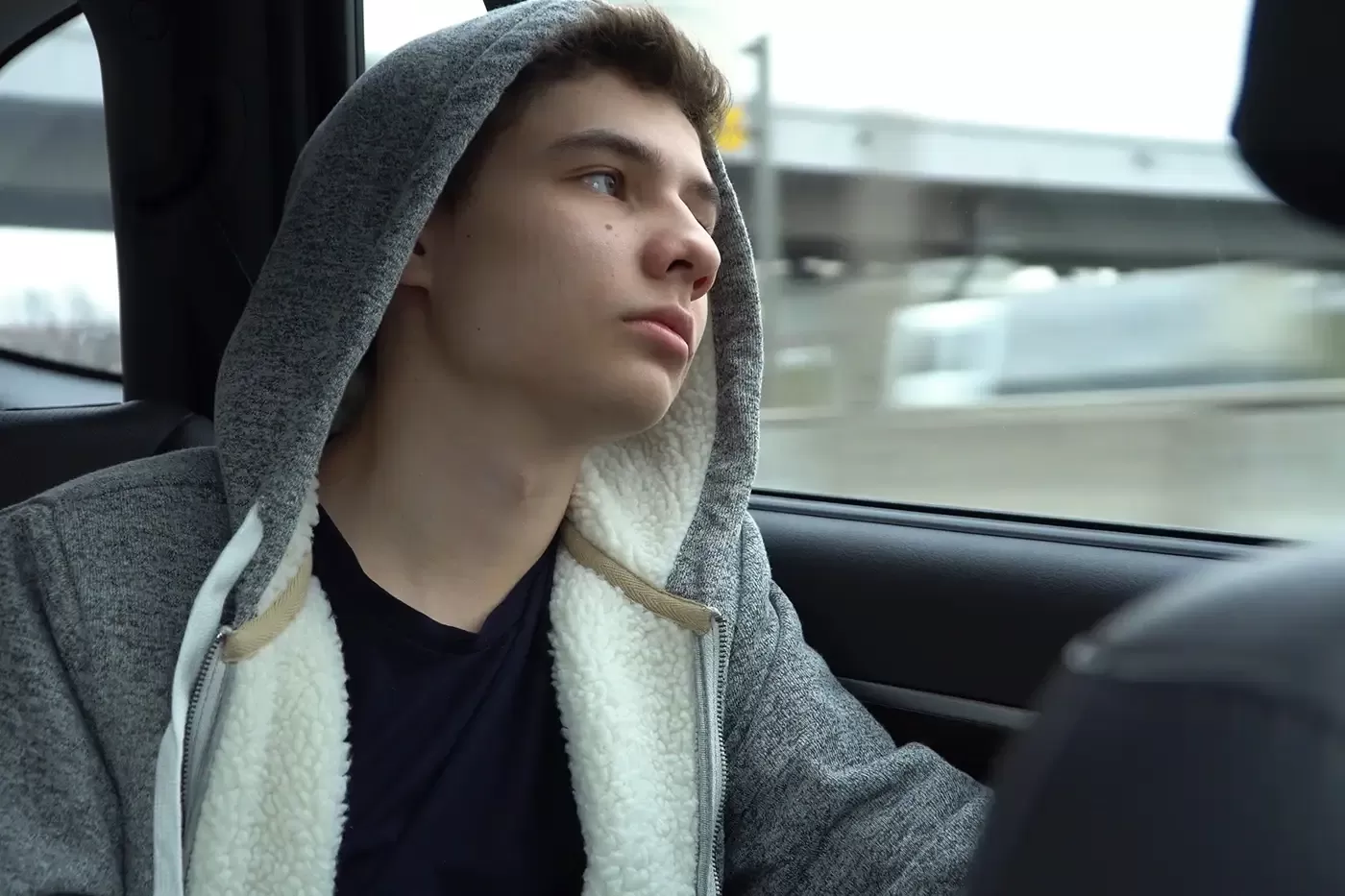 Photo of a male teen in the back seat of a car